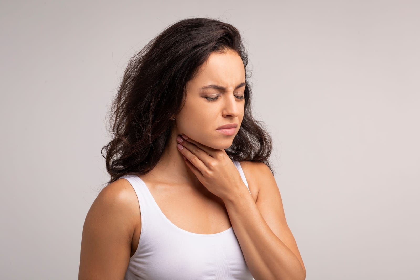 Person with tonsil stones holding throat