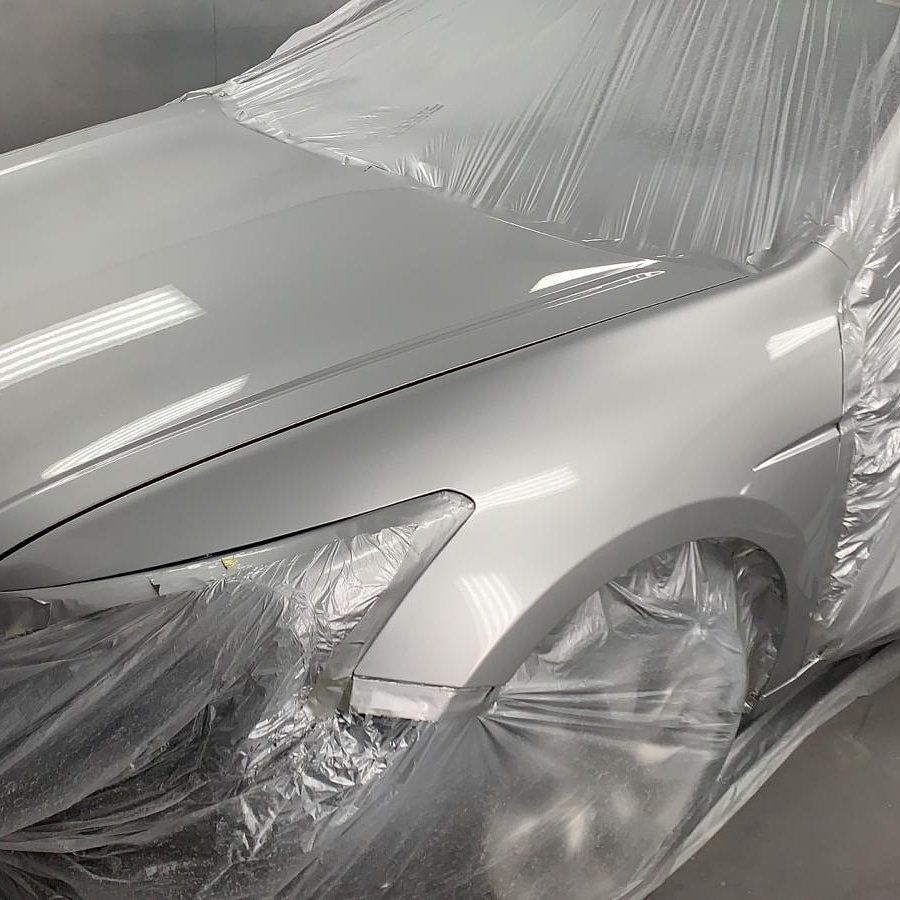 A silver car is wrapped in plastic and ready to be painted.