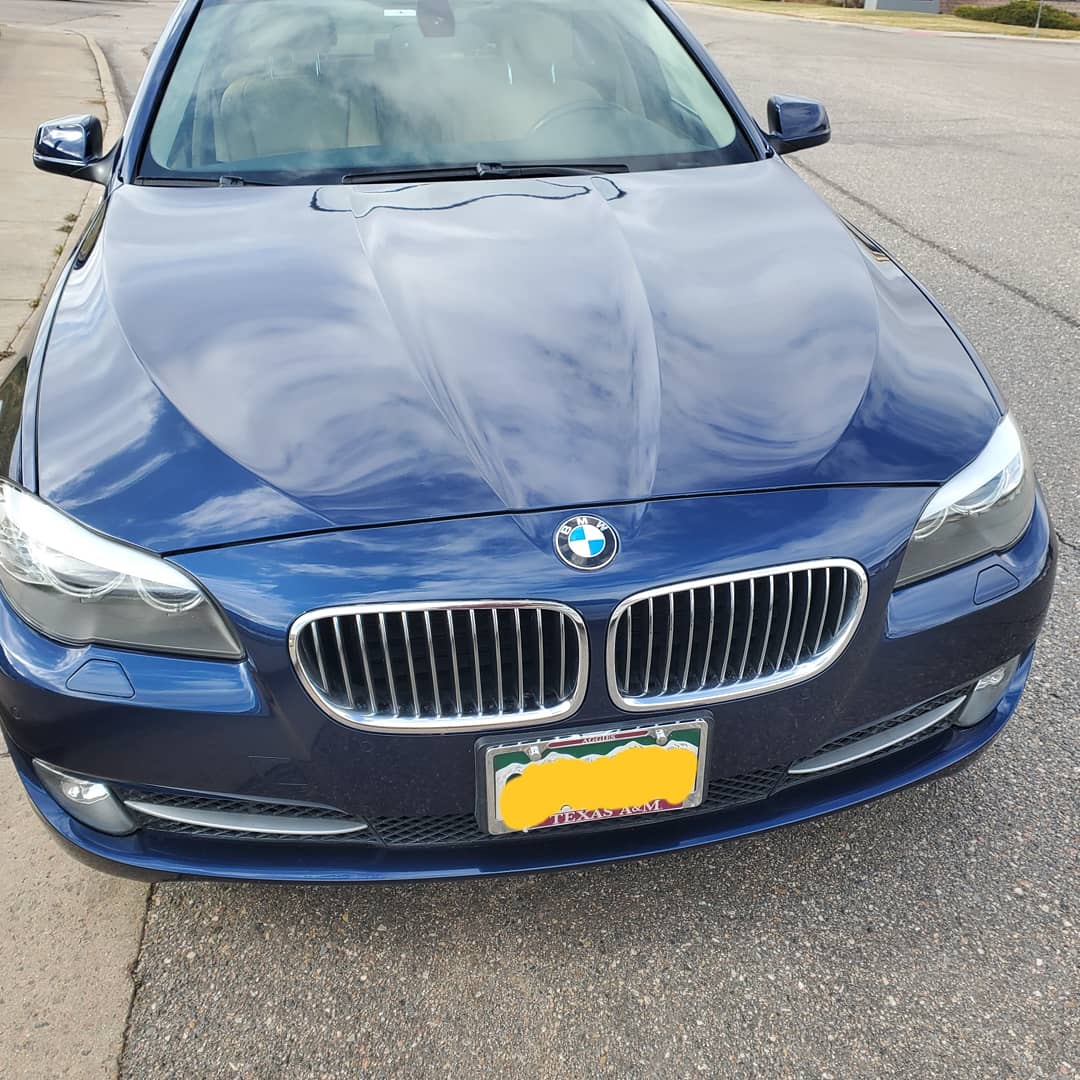 A blue bmw is parked on the side of the road