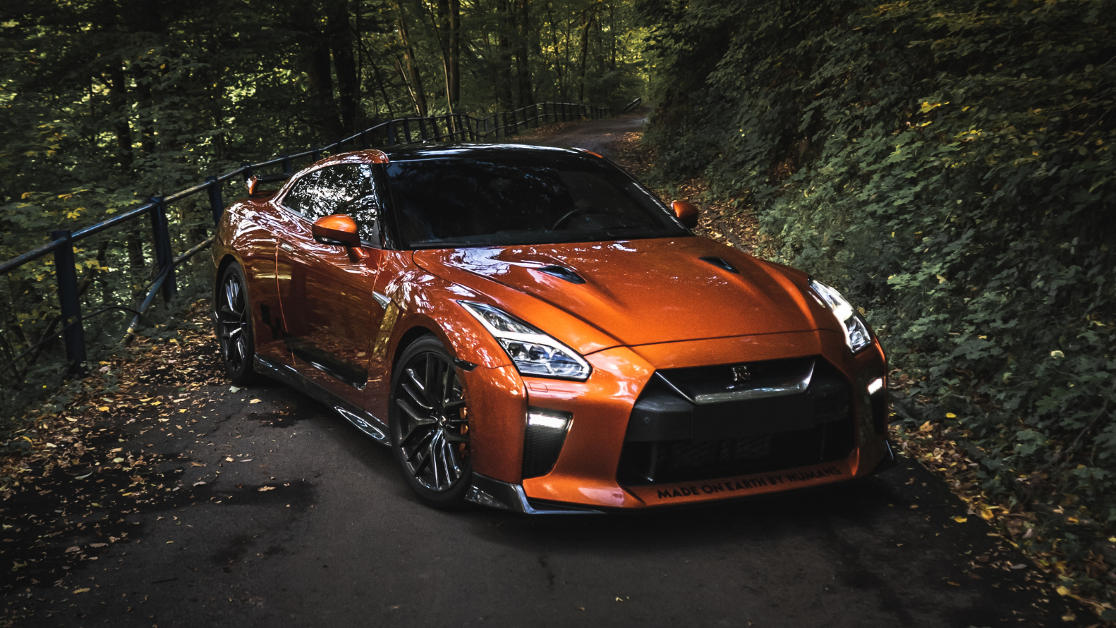 A nissan gtr is parked on the side of a road in the woods.