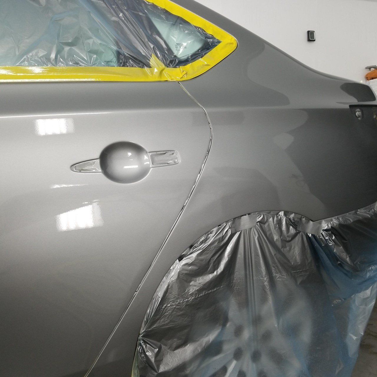 A gray car is covered in plastic and tape