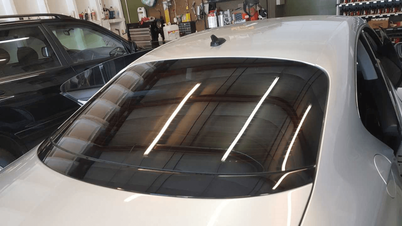 A white car with a black windshield is parked in a garage.