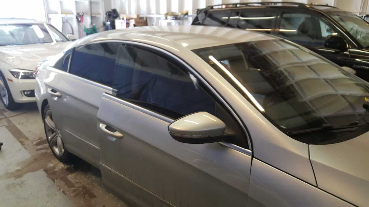 A silver car is parked in a garage next to other cars.