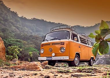 Orange vintage VW van parked on a dirt road, mountains in the background.