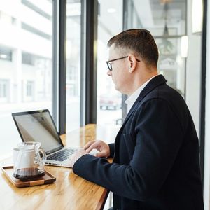 A man is sitting at a table using a laptop computer