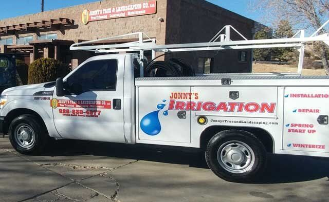 White work truck with Jonny's Irrigation logo parked outside a building.