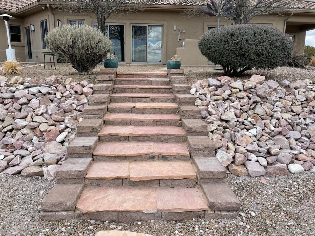 Stone staircase leading up to a house with a rock garden on either side.