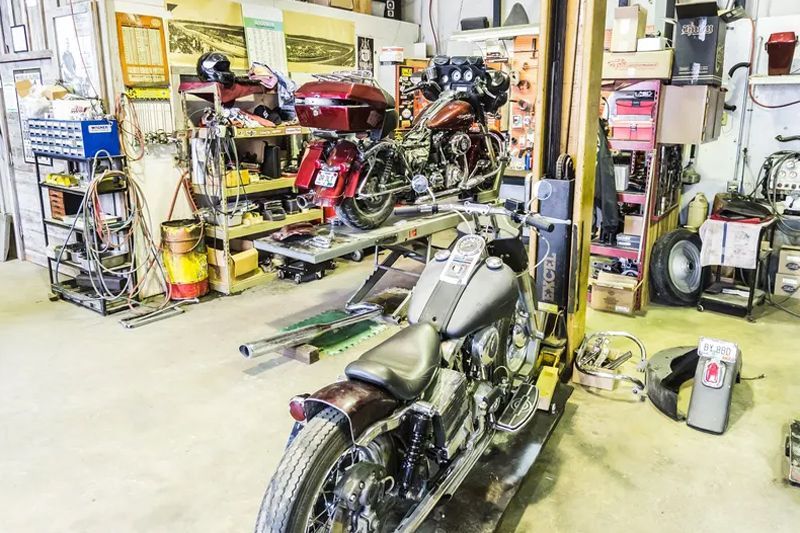 Motorcycle repair shop with two motorcycles on lifts, tools and equipment.