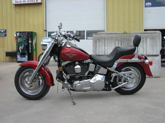 Red Harley-Davidson Fat Boy motorcycle parked outside a building with a closed garage door.