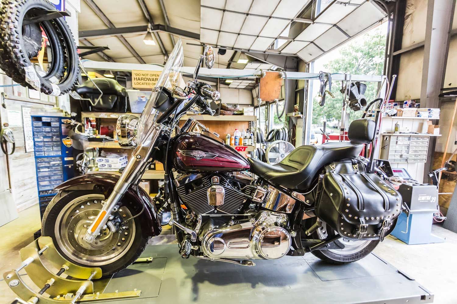 Burgundy motorcycle in a garage with tools and parts.