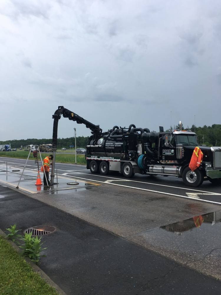 Un camion aspirateur noir est garé sur le bord de la route.