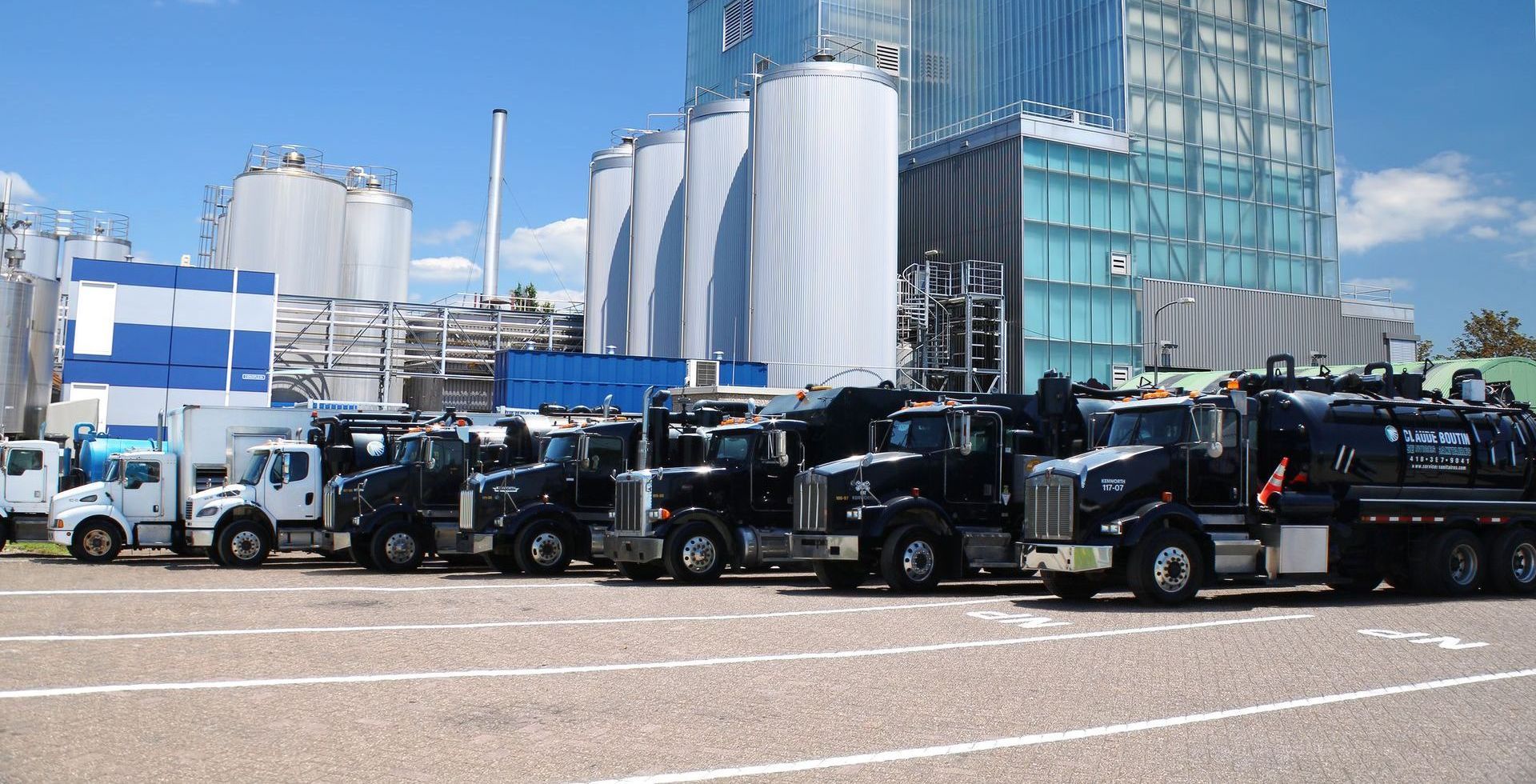 Une rangée de camions est garée sur un parking devant une usine.