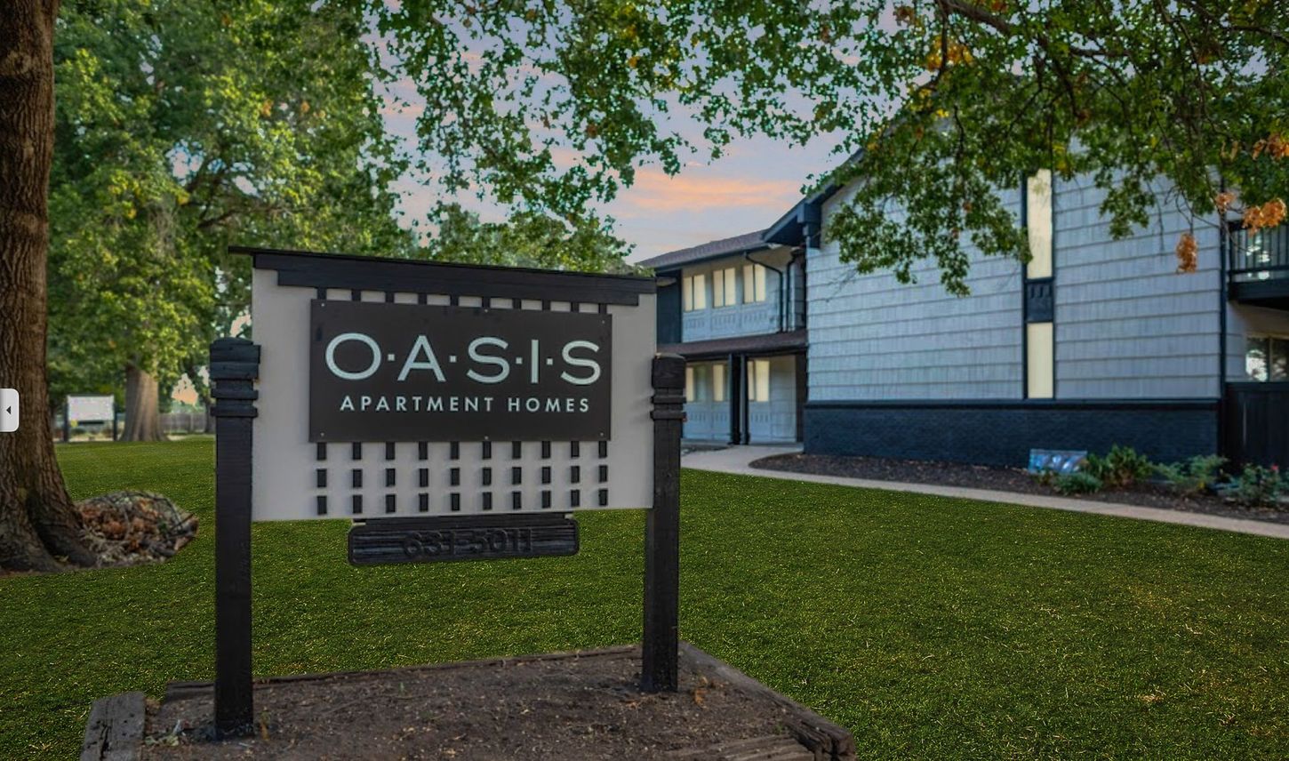 a sign for oasis apartment homes with an arrow pointing to the right
