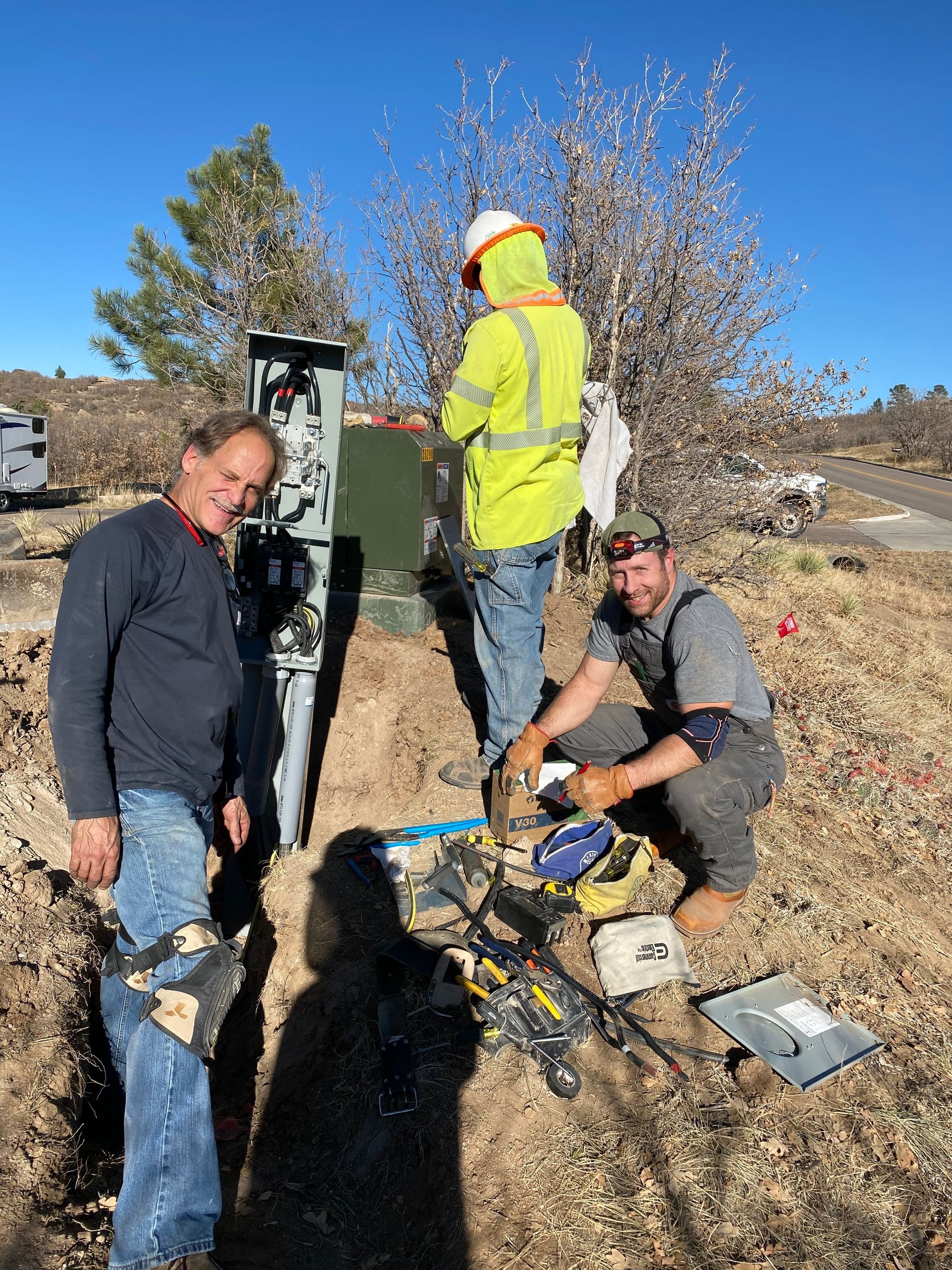 A group of men are working on a power box in a field.