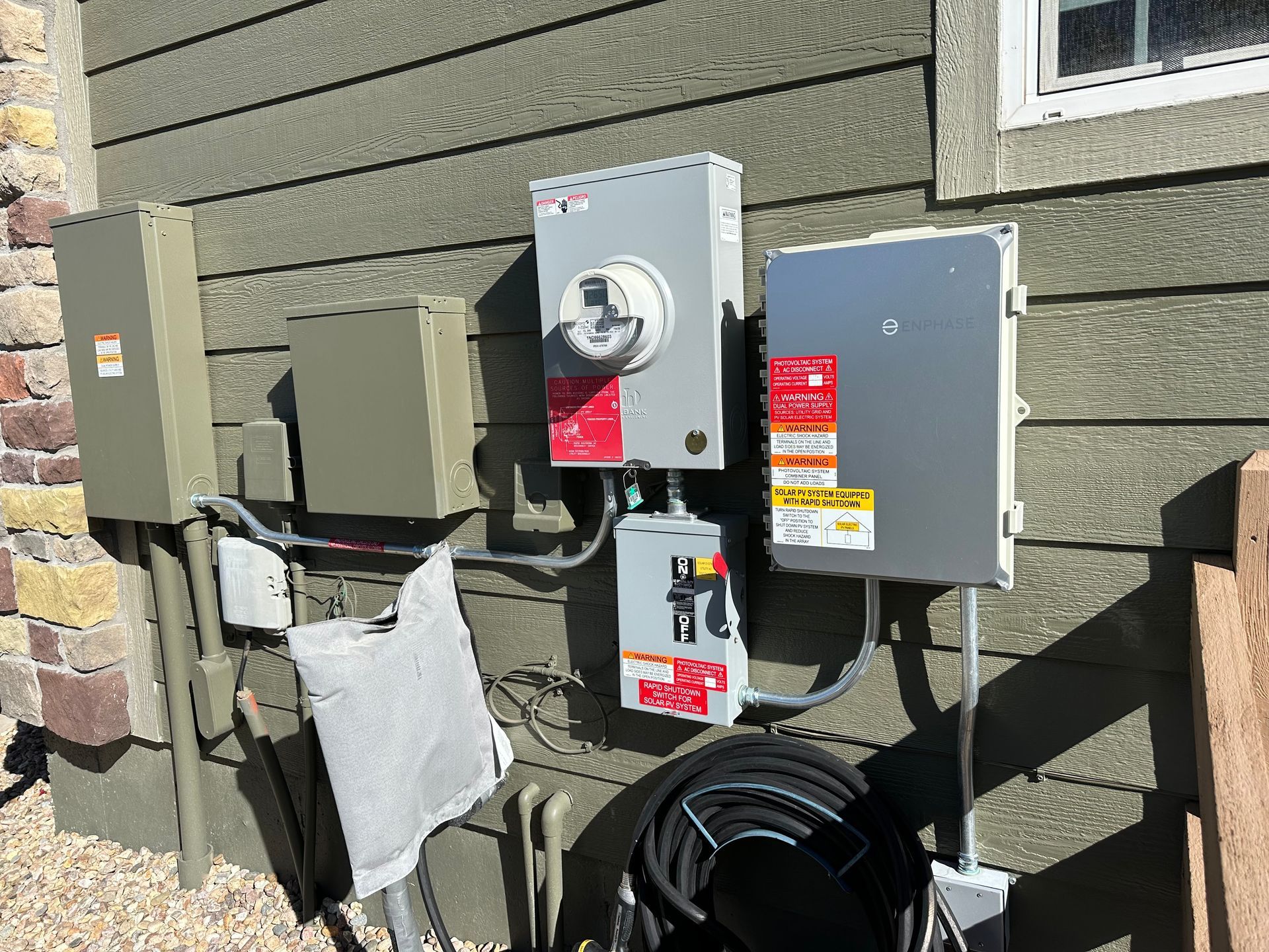There are a lot of electrical boxes on the side of a house.