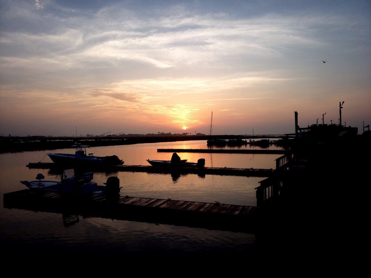 Boats are docked at a marina at sunset