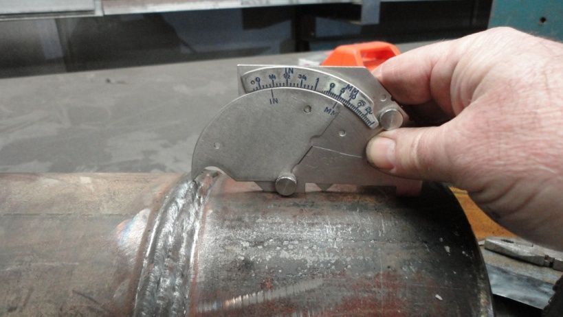 A person is measuring a piece of metal with a tool.