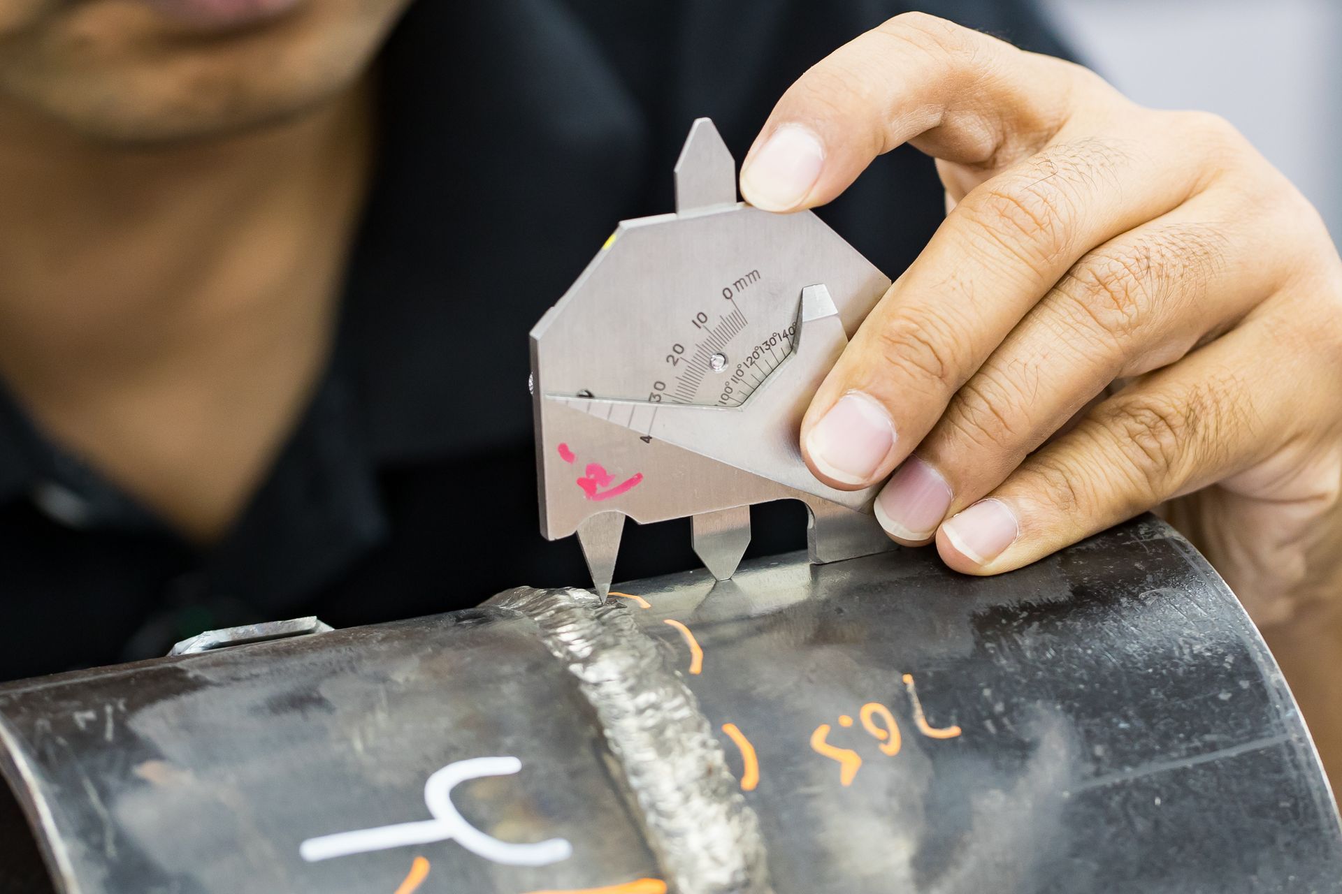 A man is measuring a piece of metal with a gauge.