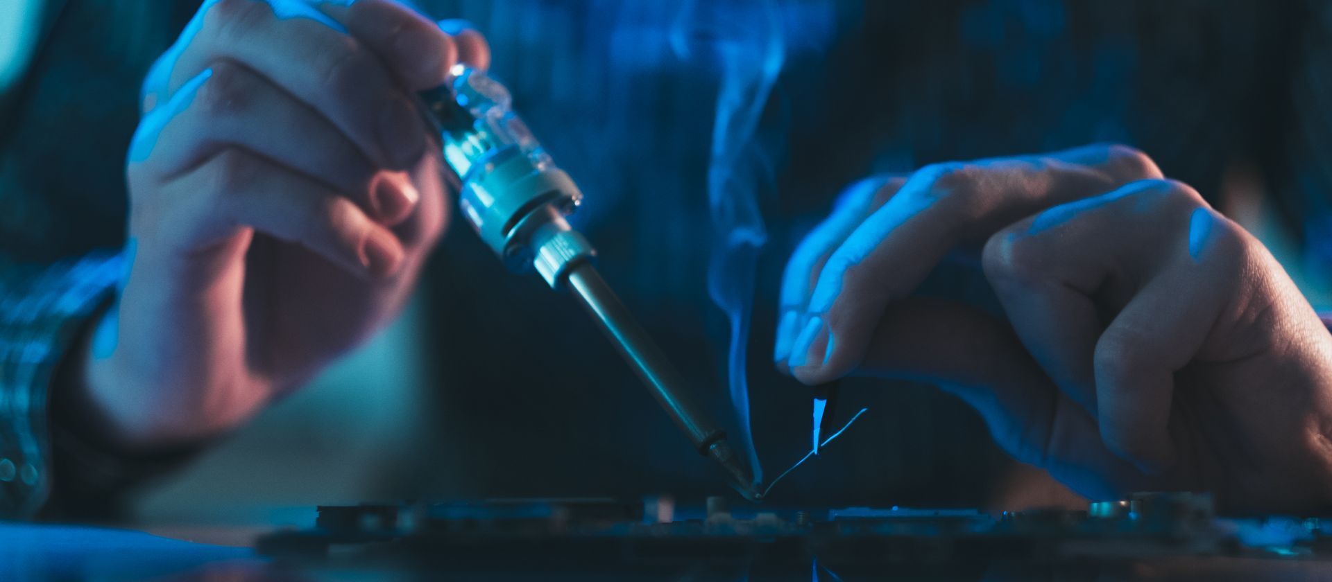 A close up of a person using a soldering iron on a motherboard.