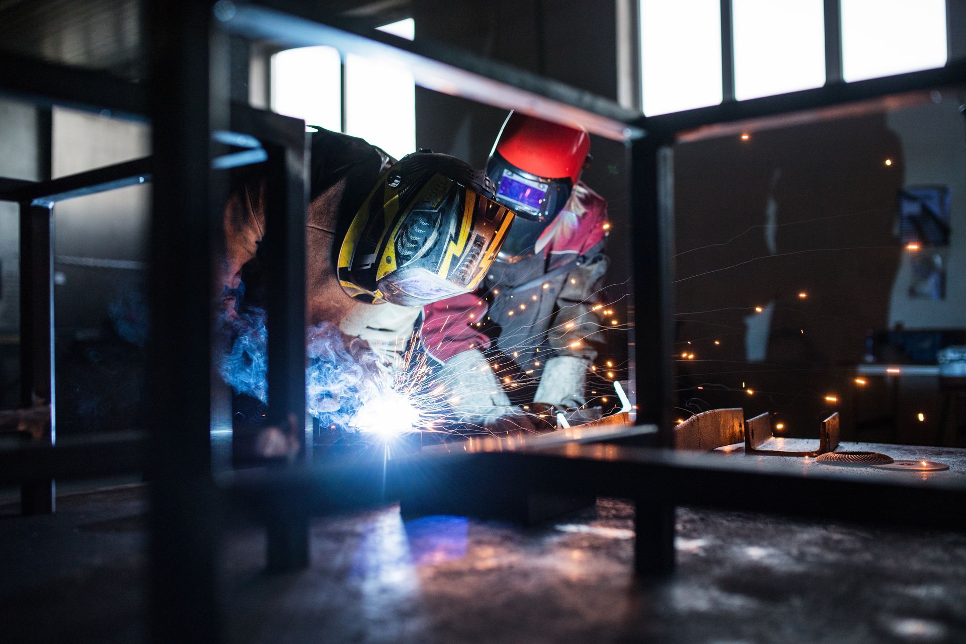 A man is welding a piece of metal in a factory.