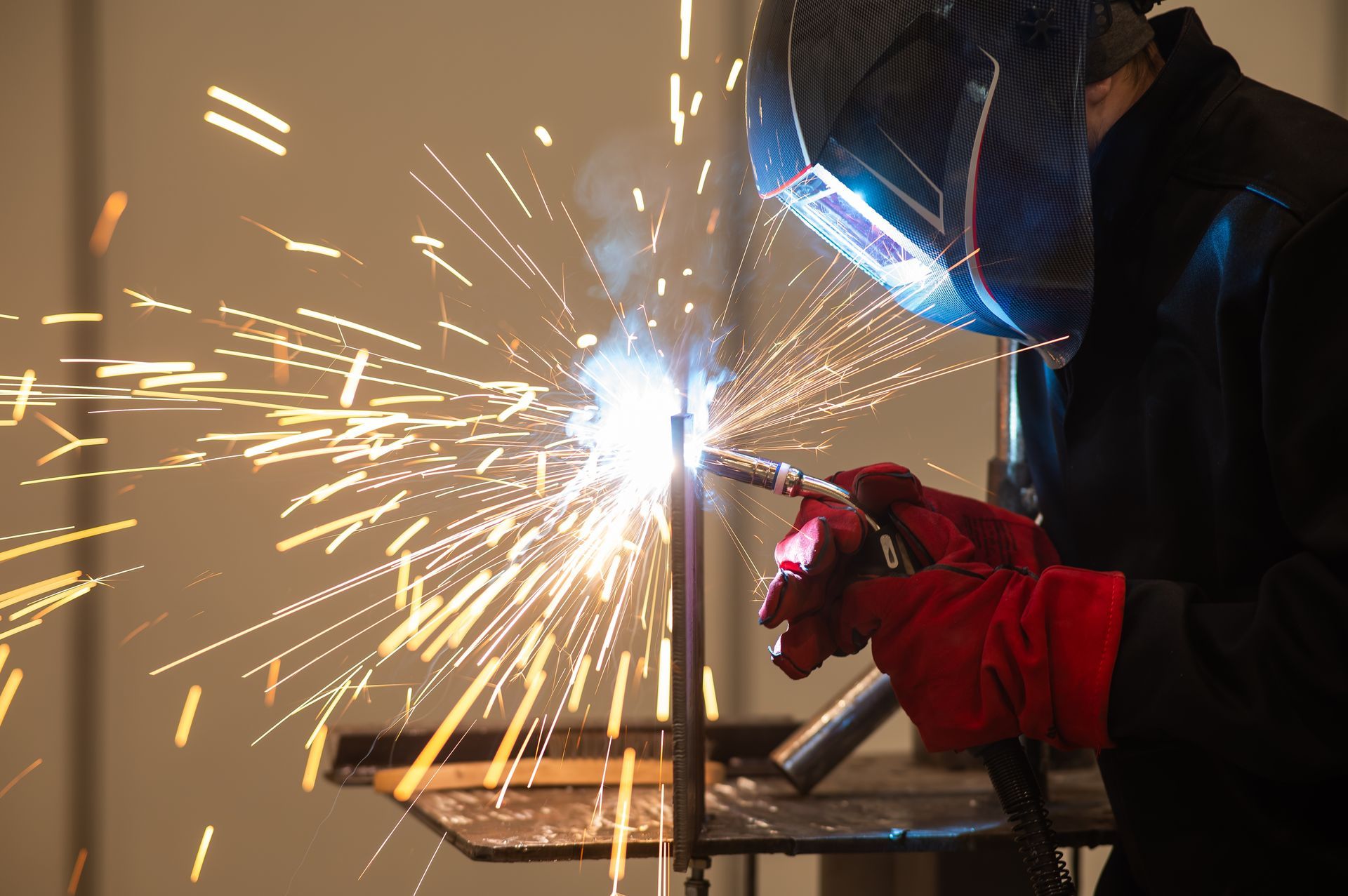 A man is welding a piece of metal in a factory.