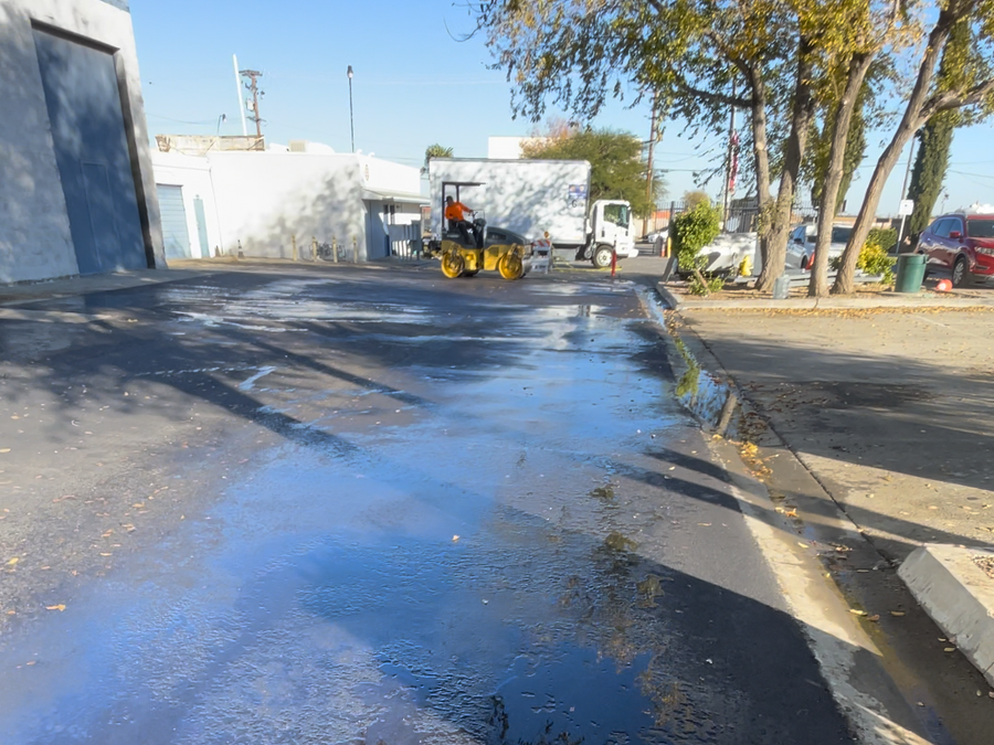 An aerial view of a man laying asphalt on a road.