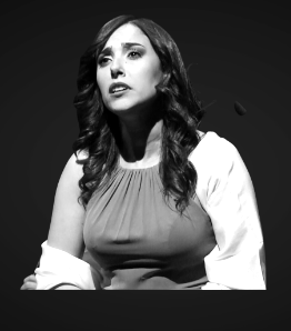 Woman singing, looking upwards with a serious expression, in a red dress with white sleeves.