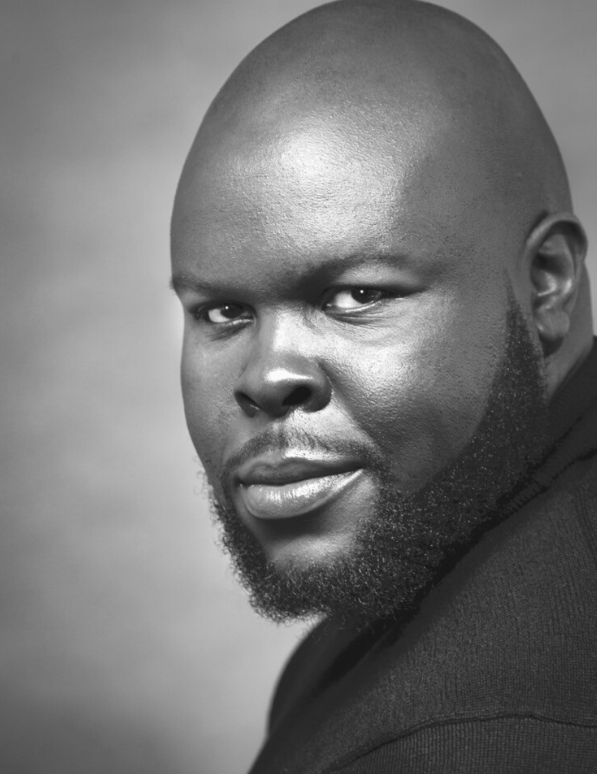 Black and white headshot of a bald man with a beard, looking to the camera with a slight smile.