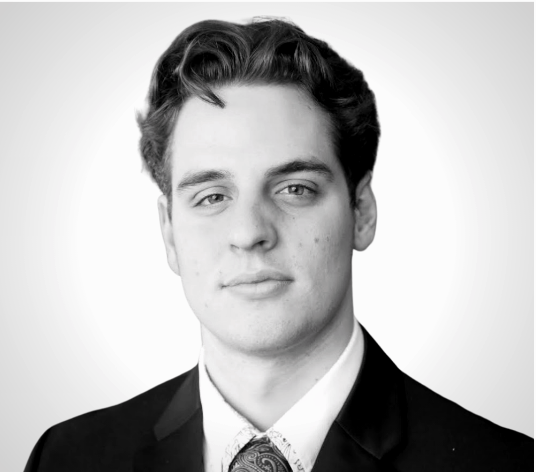 Man in a suit, looking directly at the camera with a neutral expression, grayscale headshot.