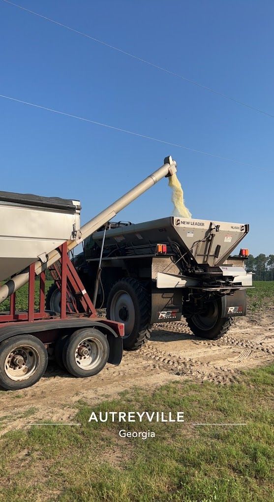 A truck is loading grain into a trailer in a field.