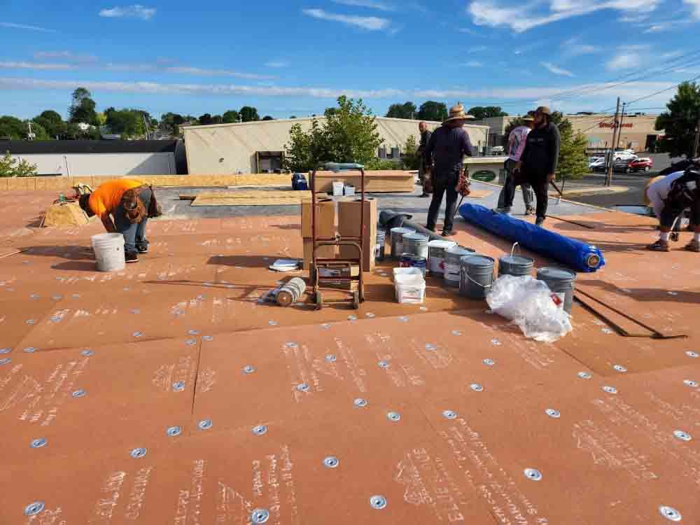 Woman in straw hat smiles, holding wine glass near a lake.