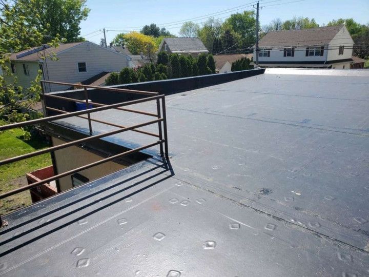 Woman in straw hat smiles, holding wine glass near a lake.