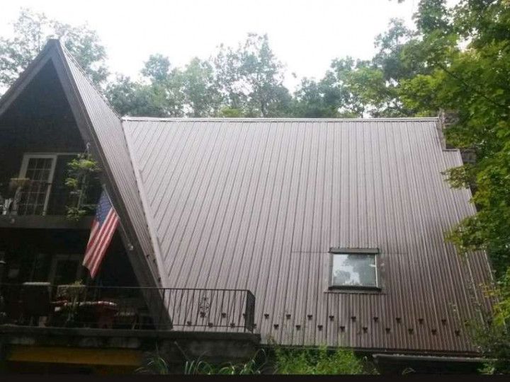 Woman in straw hat smiles, holding wine glass near a lake.