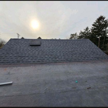 Woman in straw hat smiles, holding wine glass near a lake.