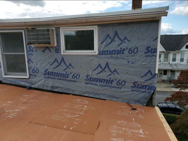 Woman in straw hat smiles, holding wine glass near a lake.