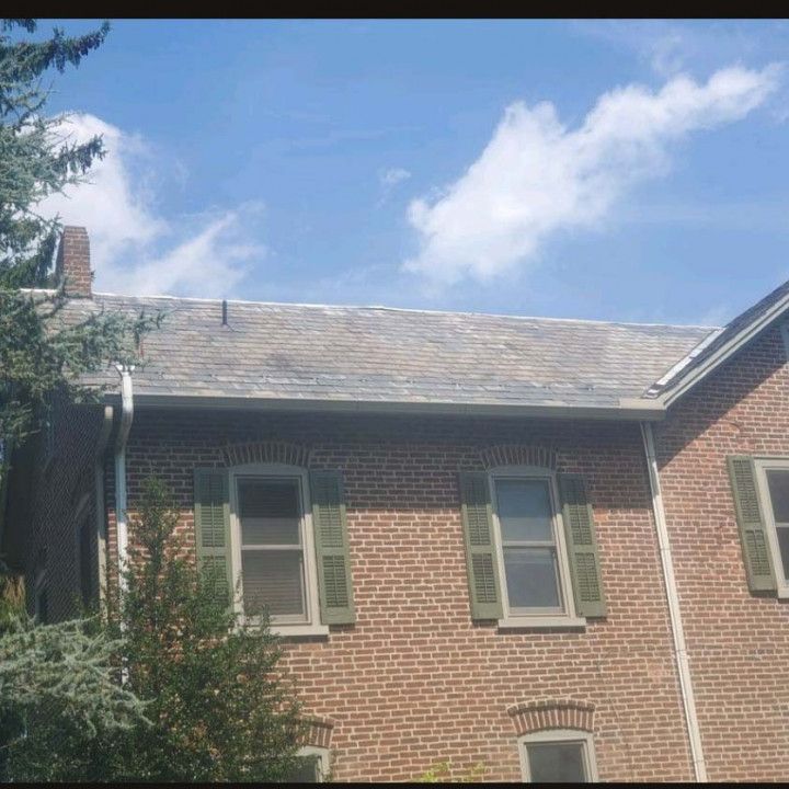 Woman in straw hat smiles, holding wine glass near a lake.
