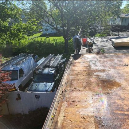 Woman in straw hat smiles, holding wine glass near a lake.