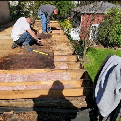 Woman in straw hat smiles, holding wine glass near a lake.