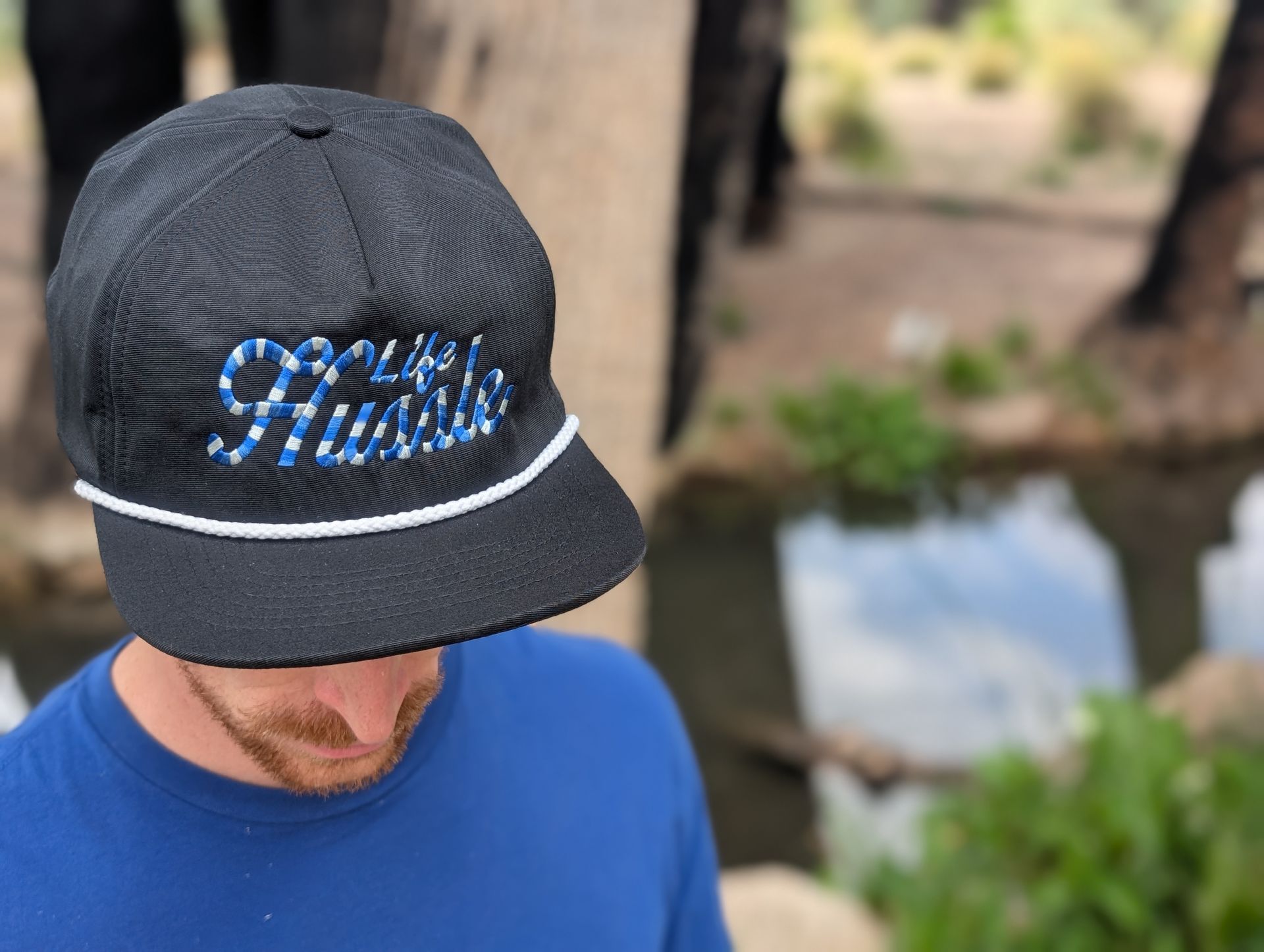 A man wearing a black hat with the word hustle on it