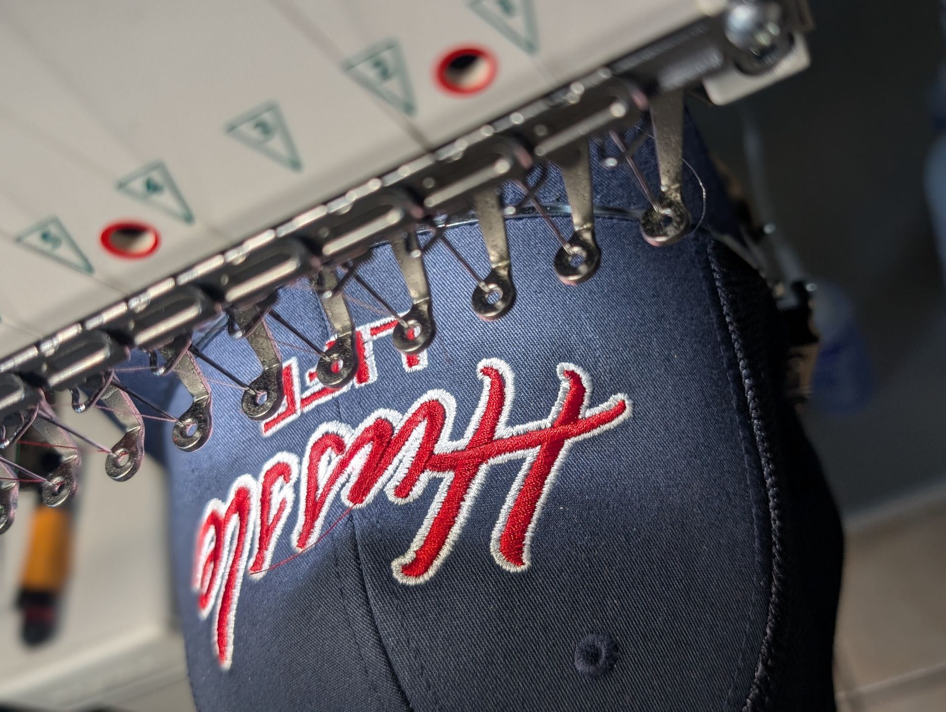 A hat is being embroidered on a machine with the word hawaii on it