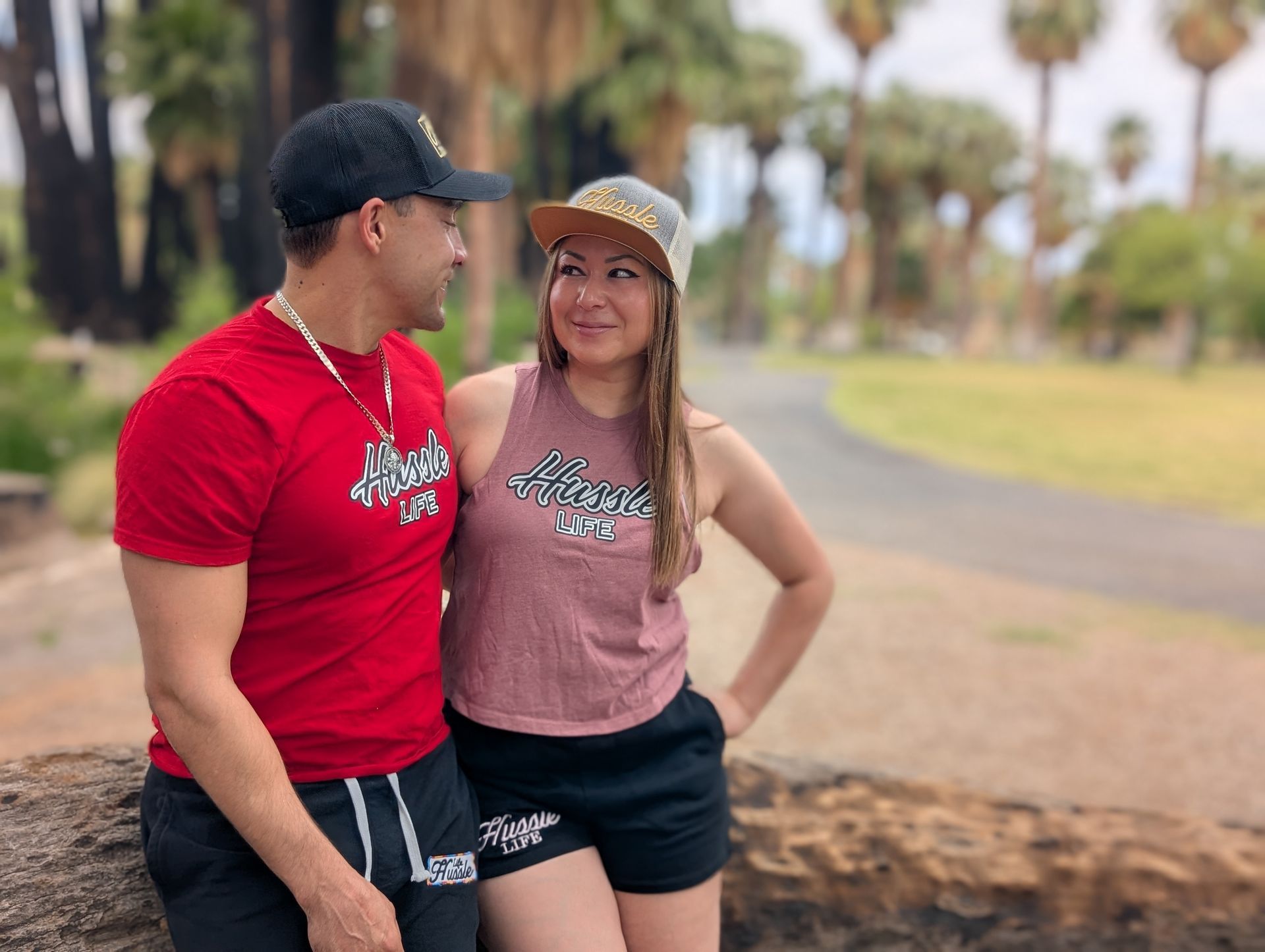 A man and a woman are standing next to each other on a log in a park.