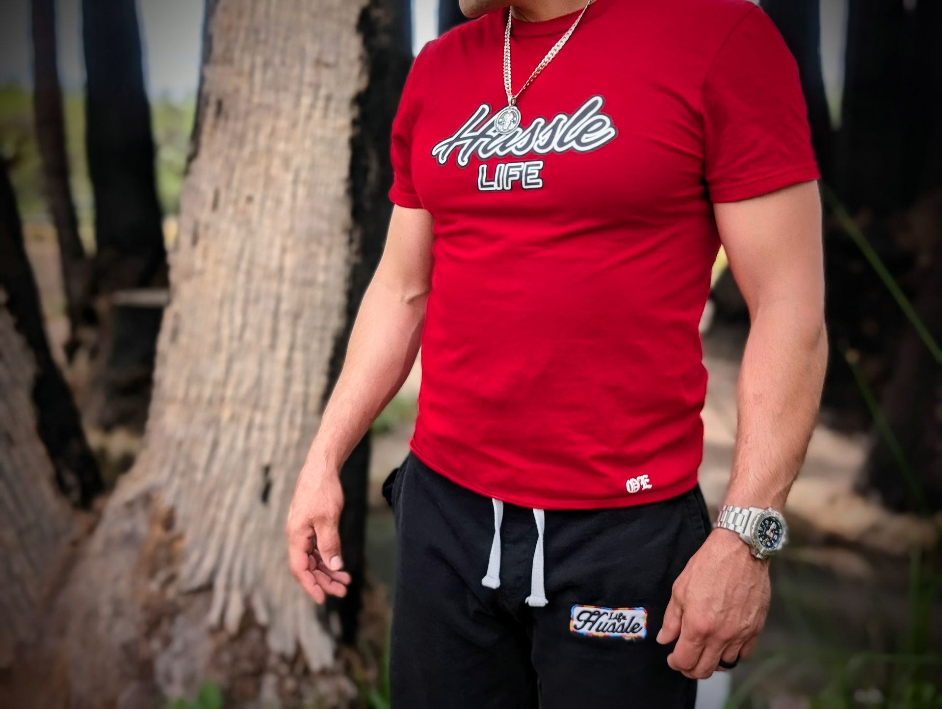 A man wearing a red shirt that says hustle life