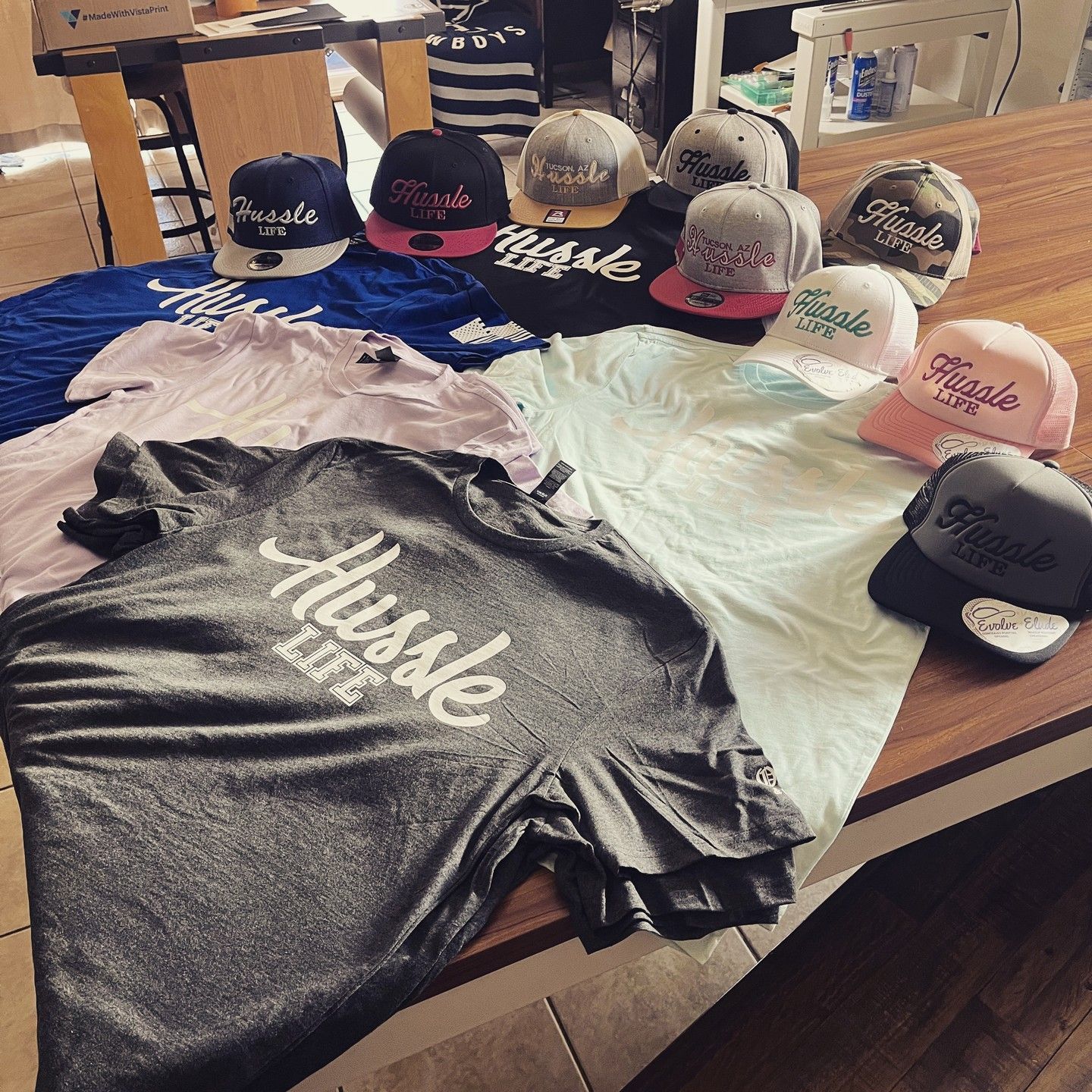 A bunch of hustle hats and shirts on a table