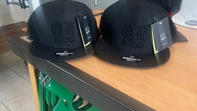 Two black hats are sitting on a wooden table.