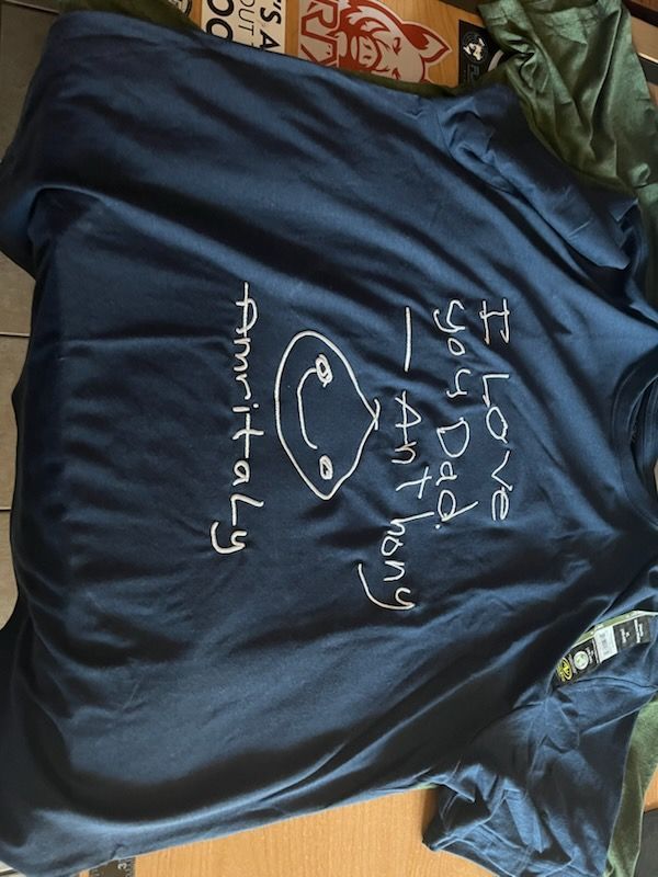 Blue shirt with handwritten message, a smiley face, and names 