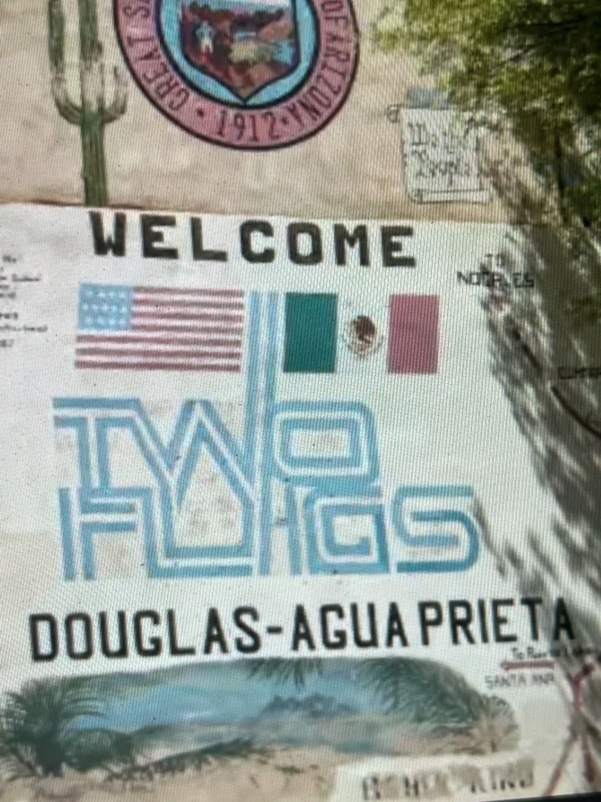 Welcome sign: American and Mexican flags, 