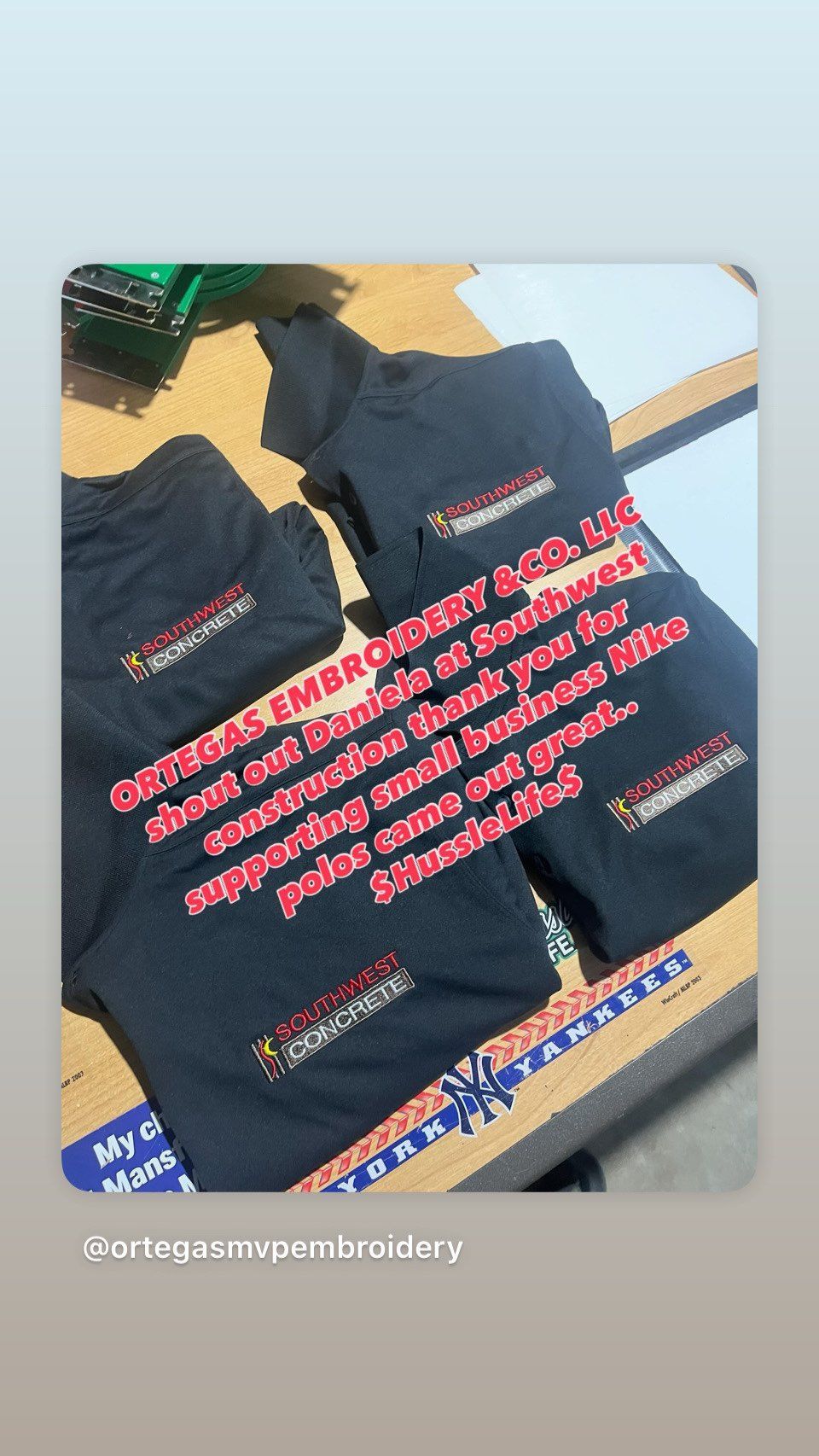 Black t-shirts with embroidered logo on a table. Text promotes a local business, 