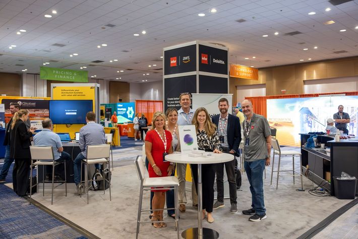 A group of Infor execs stands in their booth at TUG CONNECTS