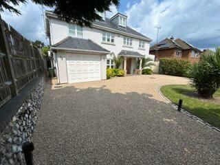 A white two-story house with a gravel driveway and a garage.