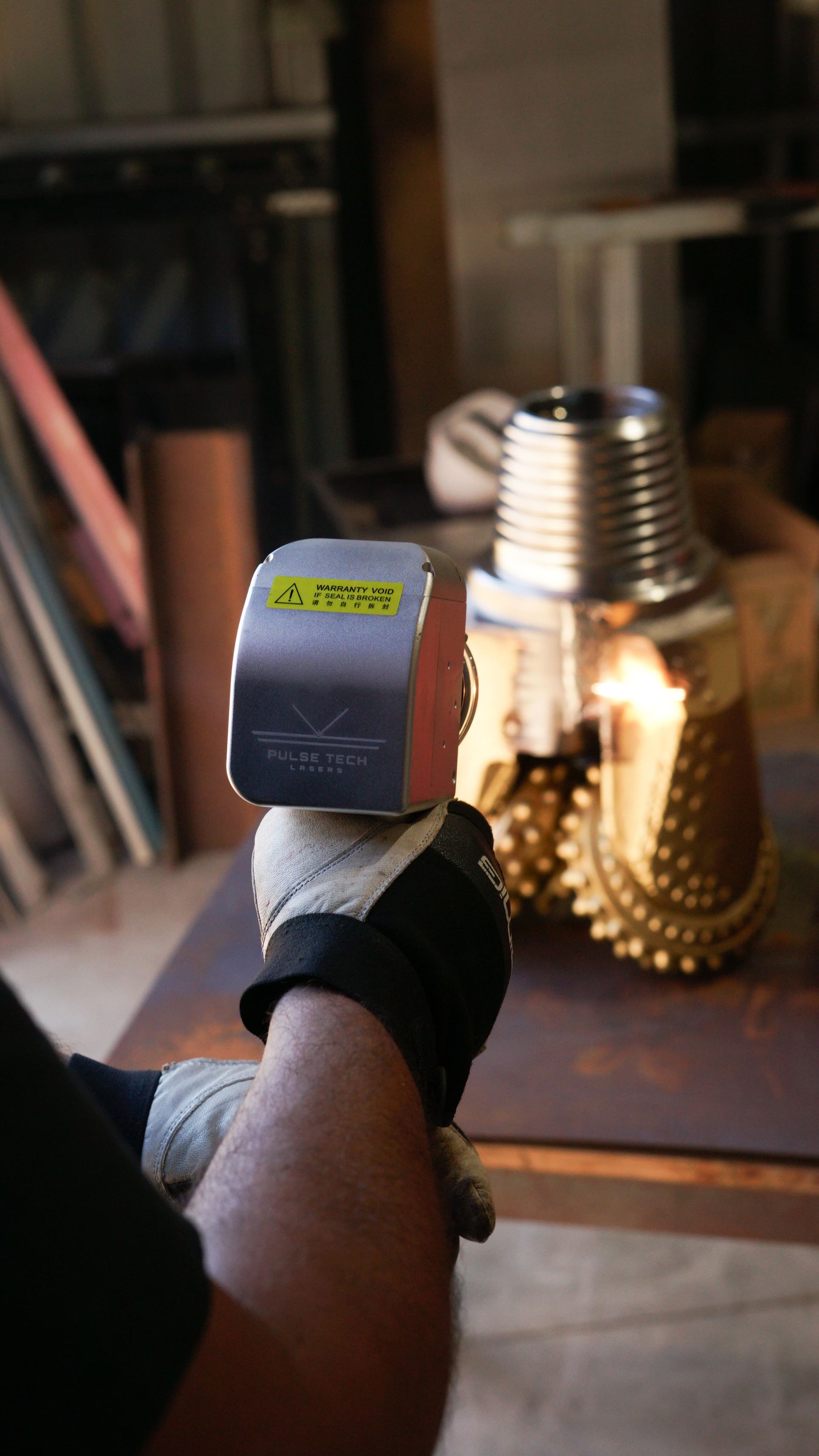 A person is holding a tool in their hand in front of a metal object.